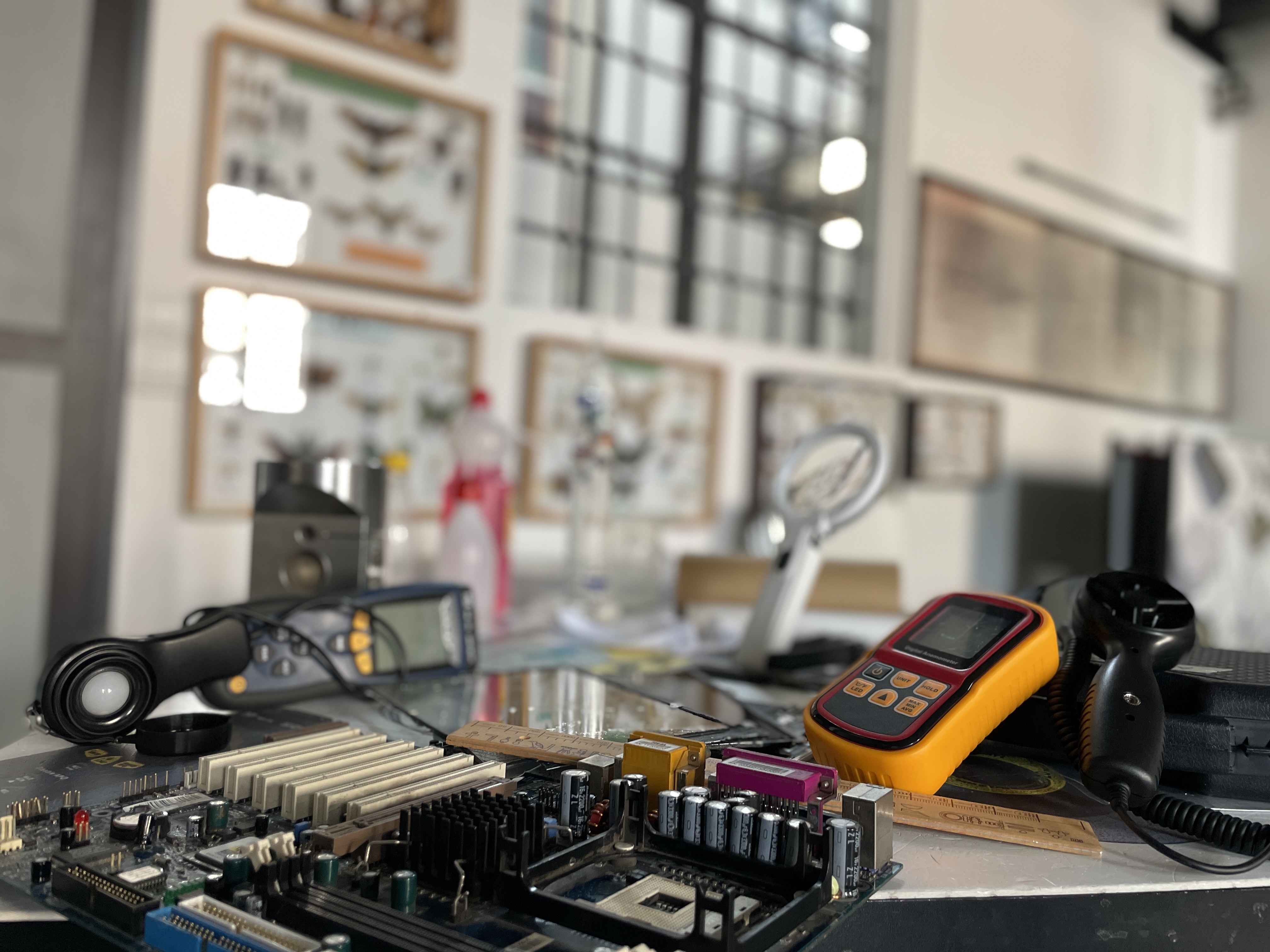 In una sala espositiva del museo, su un tavolo ci sono, un circuito con microprocessori, condensatori e schede hardware, un misuratore di spessore digitale e un righello di legno.